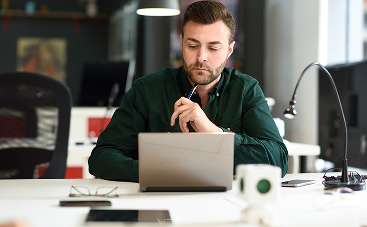 Focused man working on a laptop in a cozy office setting.